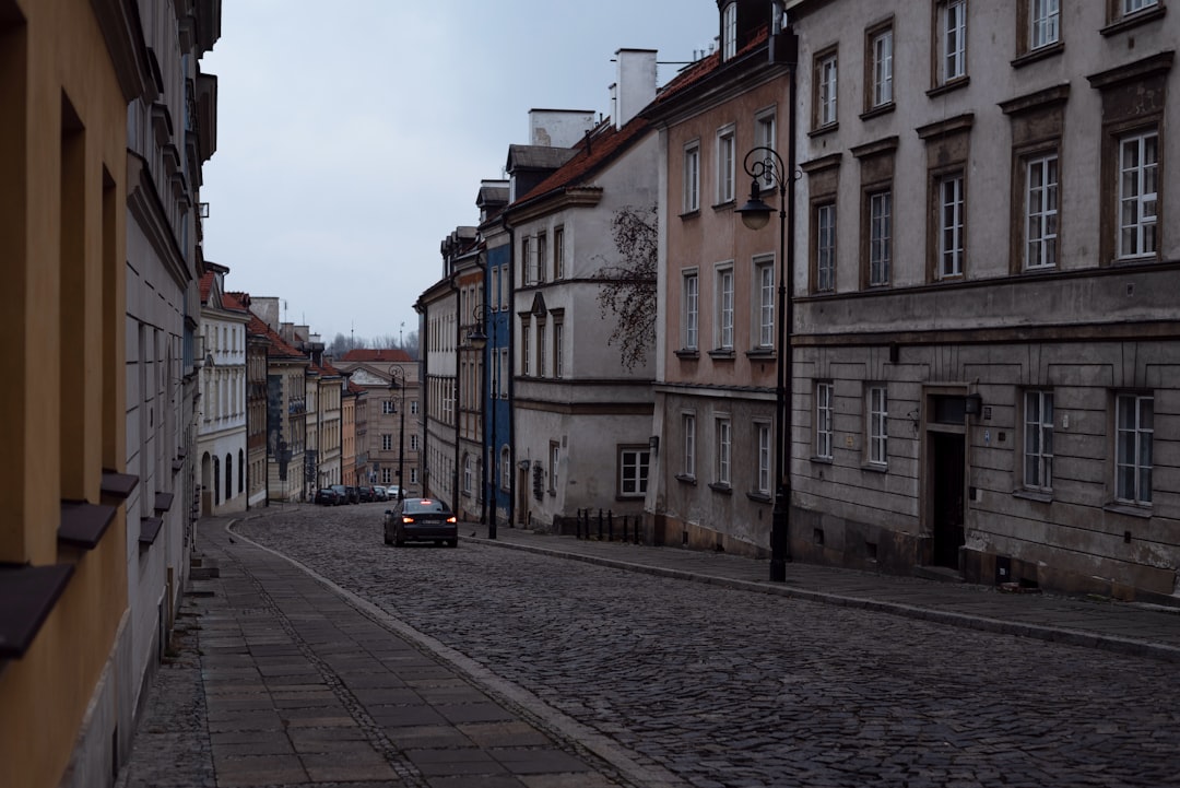 a car driving down a cobblestone street next to tall buildings